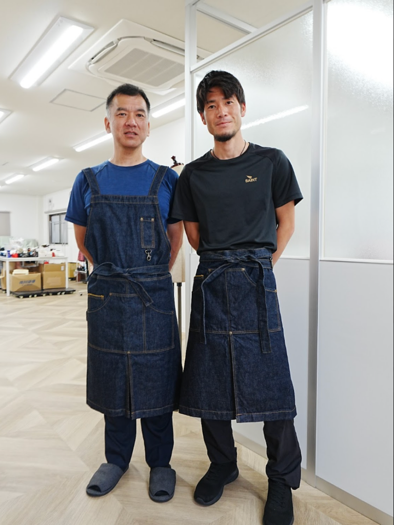 NY NOW出品用の新作デニムエプロンとデニムギャルソンエプロン。(左)プロ人材機構代表高橋啓(右)松井商店取締役松井俊介氏